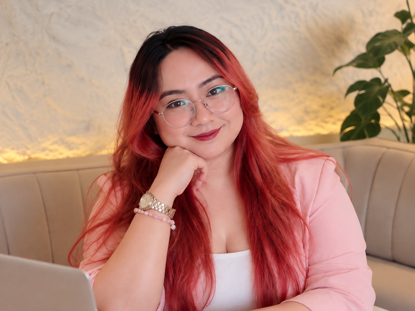 Graziel in a pink blazer and glasses, seated at her laptop